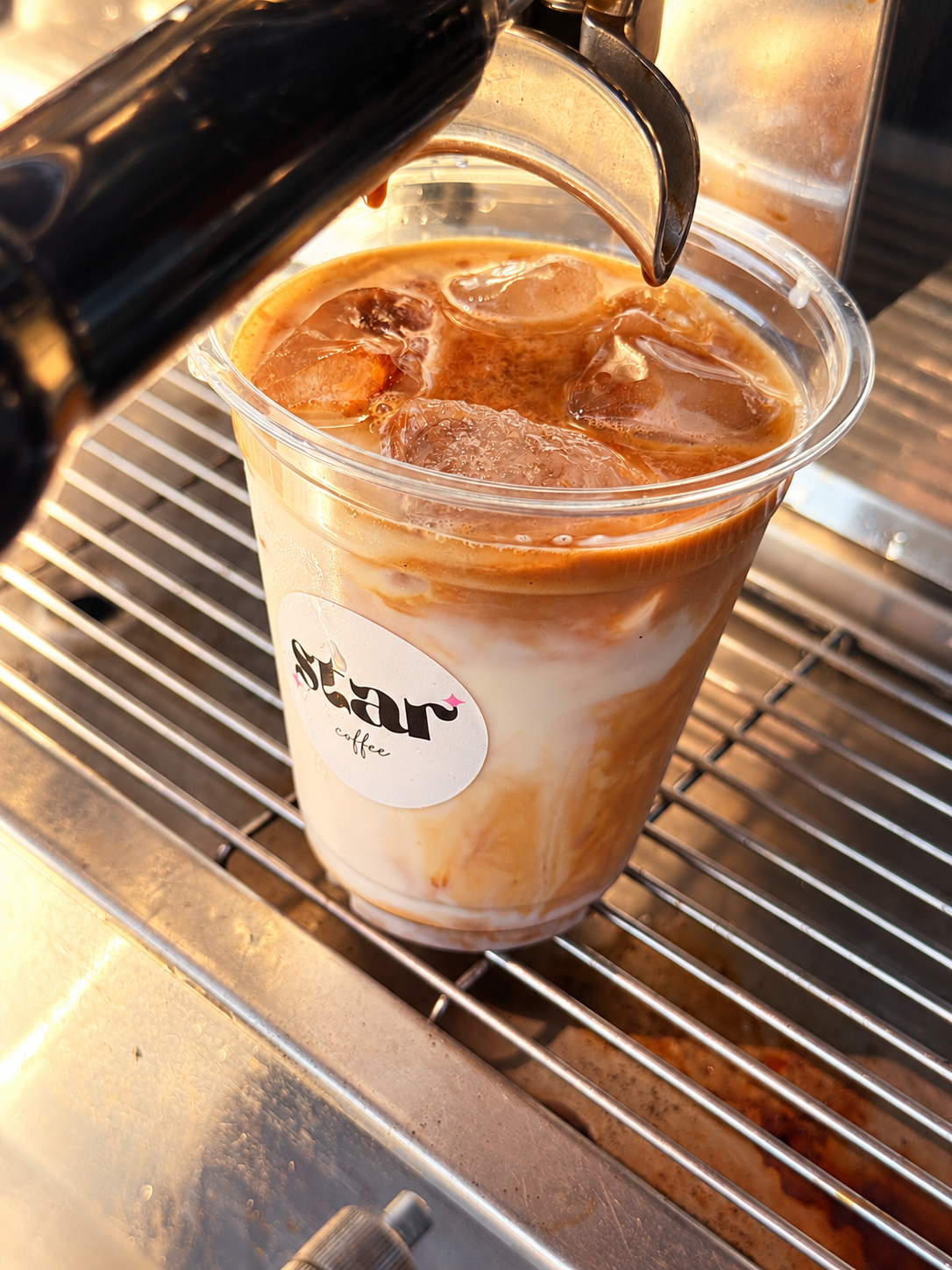 Espresso poured over ice and milk in a Star Coffee cup