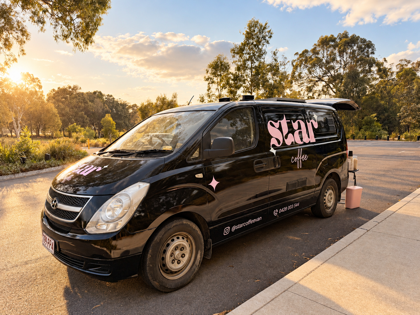 The black-and-pink Star Coffee van parked among trees